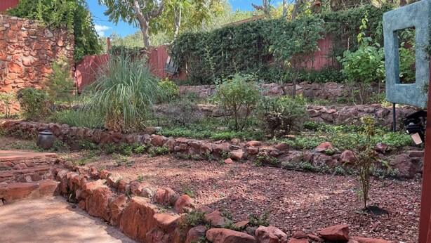 A garden with a stone wall, a small tree, and a red fence. - Private Writers Room at SaddleRock Ranch in Heart of Sedona (Sedona)