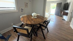 Un comedor con una mesa redonda de madera, cuatro sillas y un jarrón de flores.