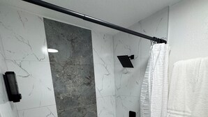 Ein Badezimmer mit Dusche, Toilette und Marmorwänden.