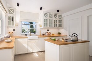 Een moderne keuken met witte kasten, een houten aanrechtblad en een raam dat natuurlijk licht binnenlaat.