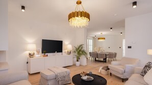 A modern living room with a flat-screen TV, a chandelier, a dining area, and a sofa. - Villa Verde Ra anj With Heated Pool (Rogoznica)