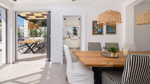 A modern dining area with a wooden table, striped chairs, and a hanging wicker light fixture. - Villa Verde Ra anj With Heated Pool (Rogoznica)