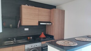 Eine kleine Küche mit Holzausstattung, einer integrierten Waschmaschine, einem Herd und einer modernen Arbeitsplatte.