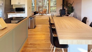 A modern kitchen with a dining area, wooden flooring, and large windows. - Secluded 5BR Cabin, Hot Tub, Views, Mt Hood (Rhododendron)