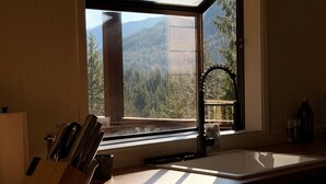 A kitchen with a large window, a knife block, and a sink. - Secluded 5BR Cabin, Hot Tub, Views, Mt Hood (Rhododendron)