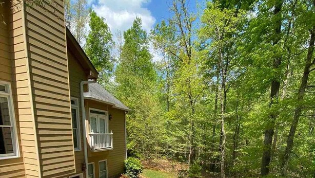 Une terrasse dotée de mobilier d’extérieur, d’un patio couvert et offrant une vue sur une zone boisée.