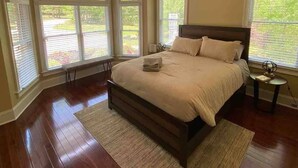 Une chambre avec un grand lit, un ventilateur de plafond et de grandes fenêtres.