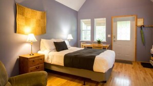 A bedroom with a bed, bedside tables, a chair, a desk, and a window.
