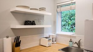 A kitchen with white shelves, a window, a sink, and a toaster.