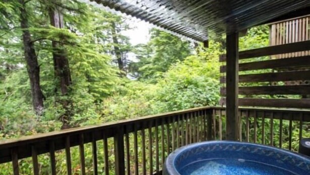 A hot tub on a wooden deck with a view of a forest.