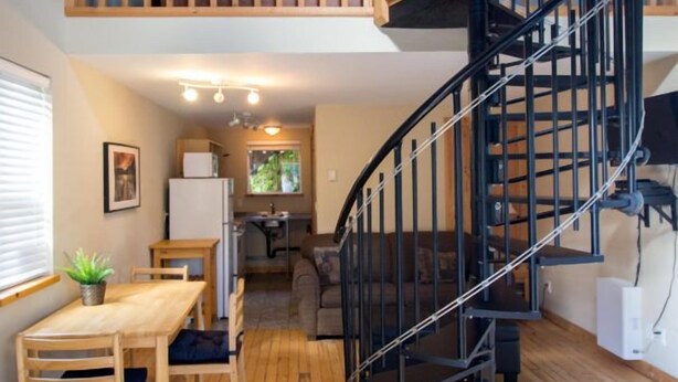 A compact living space with a spiral staircase, a dining area, and a kitchenette.