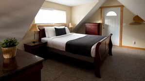A bedroom with a bed, bedside tables, a nightstand, a lamp, a dresser, a window, and a door.