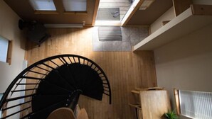 A spiral staircase in a room with wooden flooring, a radiator, and a small plant.