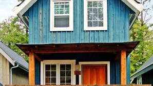 Una casa de dos pisos con un porche de madera y una puerta principal.
