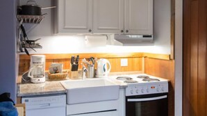Una cocina con armarios blancos, estufa, lavavajillas y cafetera.