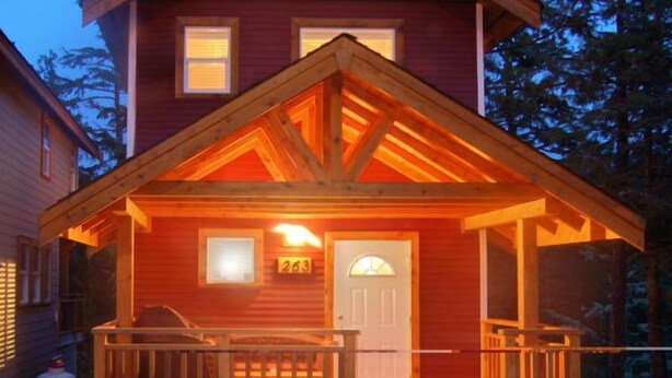 A two-story wooden house with a porch, a door with a window, and a number '263' on the wall.