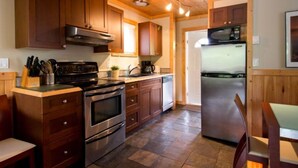 A kitchen with wooden cabinets, a stove, a microwave, and a refrigerator.