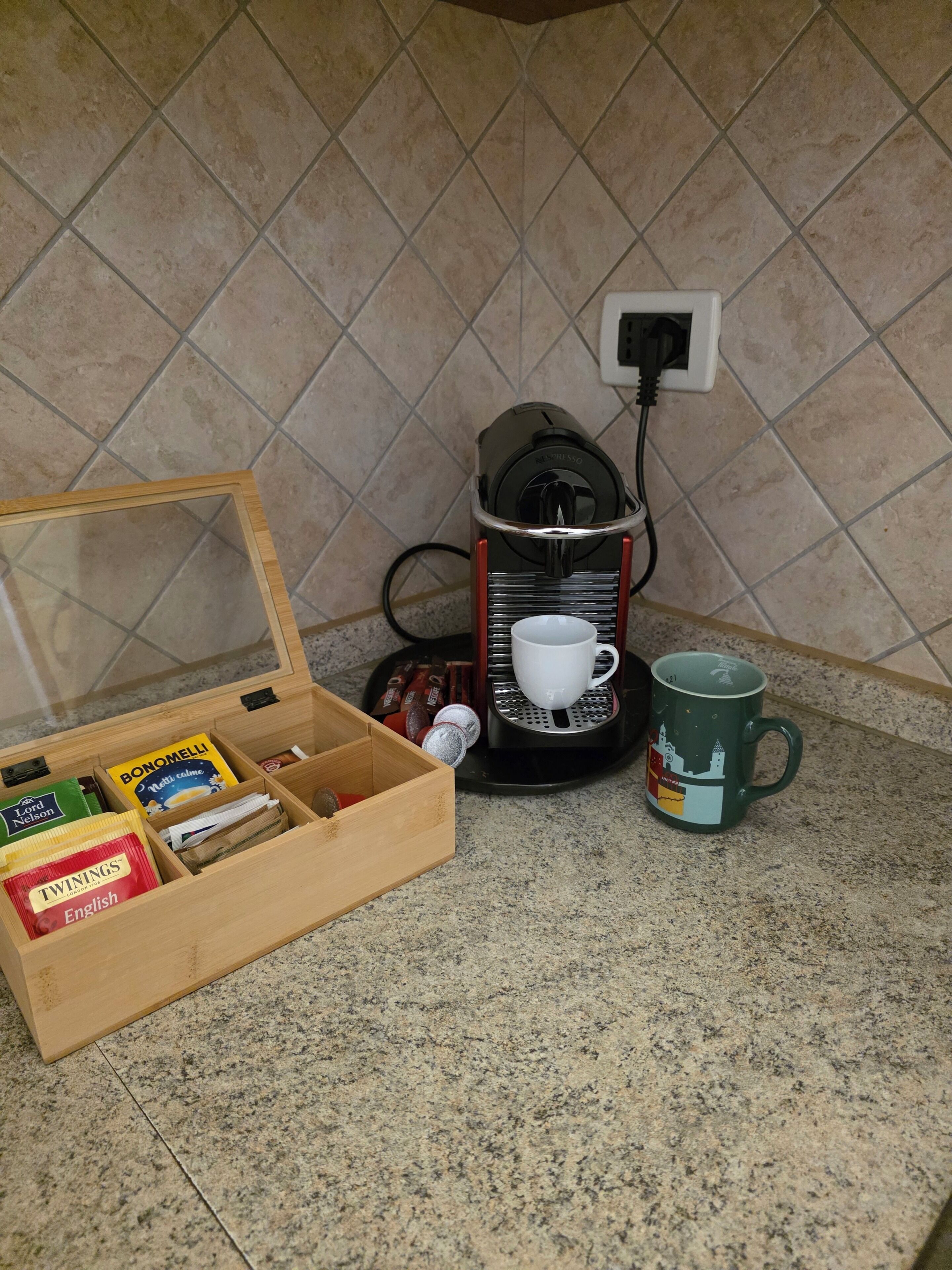Een keuken met een koffiezetapparaat, een mok en een doos koffiecups.
