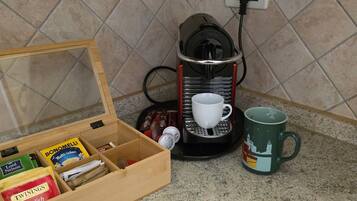 Een keuken met een koffiezetapparaat, een mok en een doos koffiecups.