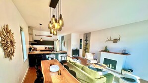 A modern living space with a dining area, kitchen, and a fireplace.