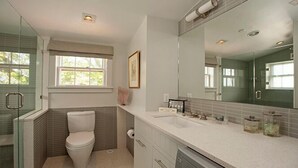 A modern bathroom with a toilet, sink, and large mirror. - 1 Bedroom, 1 bathroom (Nantucket)