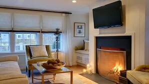 A living room with a fireplace, a television, a sofa, a chair, and a table with a bowl of snacks. - 2 bedroom, 2 bathroom (Nantucket)