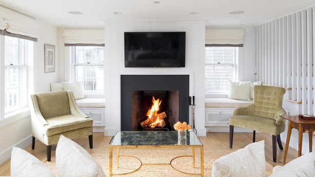 A living room with a fireplace, two armchairs, a sofa, and a TV mounted above the fireplace. - 2 bedroom, 2 bathroom (Nantucket)