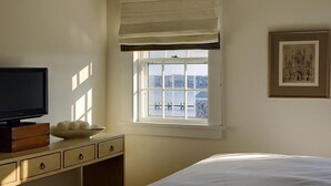 A bedroom with a bed, a TV on a wooden dresser, a window with a view, and a framed picture on the wall. - 2 bedroom, 2 bathroom (Nantucket)