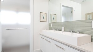 A modern bathroom with a white sink, two faucets, a mirror, and a towel rack. - 2 bedroom, 2 bathroom (Nantucket)
