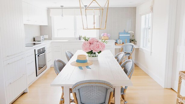 A modern kitchen with white cabinetry, a wooden dining table, and a hanging light fixture. - 2 bedroom, 2.5 bathroom (Nantucket)