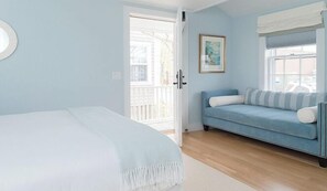 Een kamer met een bed, een blauwe bank, een deur en een raam.