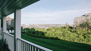 Blick von einer überdachten Veranda mit Rasen und einem Yachthafen im Hintergrund.