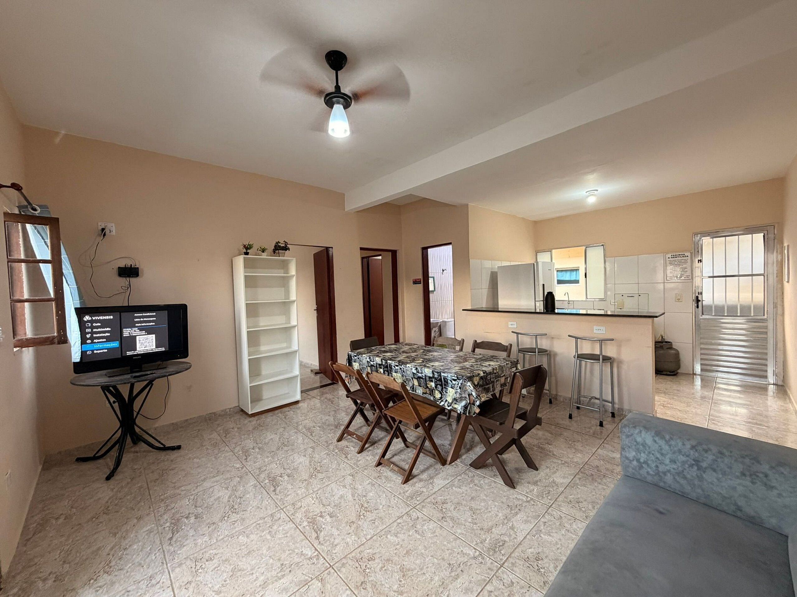 A dining area with a table, chairs, a TV, and a ceiling fan.