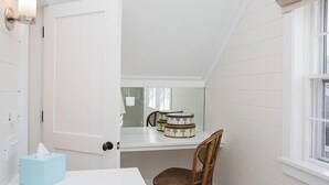 A bathroom with a white door, a towel rack, a mirror, and a chair.