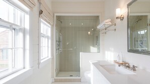 A modern bathroom with a large window, a walk-in shower, and a vanity with a sink.