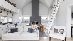 A modern kitchen with white cabinets, a dining area with a wooden table, and a staircase. - 1 Bedroom with loft, 1 bathroom (Nantucket)
