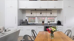 A modern kitchen with white cabinets, a wooden dining table, and a vase of flowers. - 1 Bedroom with loft, 1 bathroom (Nantucket)