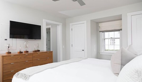 Une chambre à coucher avec un lit, une commode, un téléviseur et une fenêtre donnant sur un beau paysage.