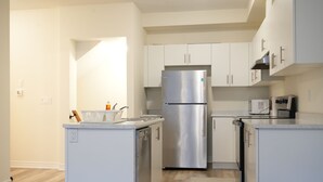 Una cocina moderna con armarios blancos, un refrigerador de acero inoxidable y un microondas.