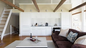 A modern kitchen with white cabinets, a dining area with a brown couch, and a staircase. - 1 Bedroom, 1 bathroom (Nantucket)