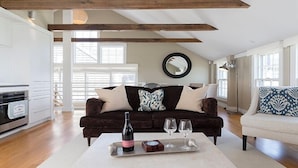 A living room with a dark brown sofa, a white sofa, a round mirror, and a wine bottle on a tray. - 1 Bedroom, 1 bathroom (Nantucket)