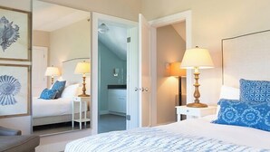 A hotel room with a bed, bedside lamps, a mirror, and a view into the bathroom. - 2 bedroom, 2 bathroom (Nantucket)