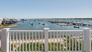 A marina with boats docked, a sandy beach, and a white fence in the foreground. - 2 bedroom, 2.5 bathroom (Nantucket)