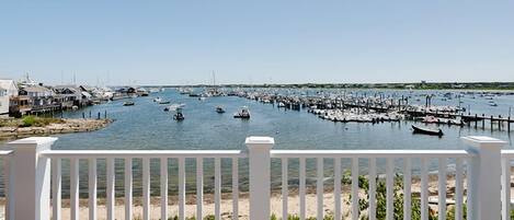 A marina with boats docked, a sandy beach, and a white fence in the foreground.