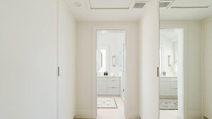 A hallway leading to a bathroom with a mirror, a sink, and a door. - 2 bedroom, 2.5 bathroom (Nantucket)
