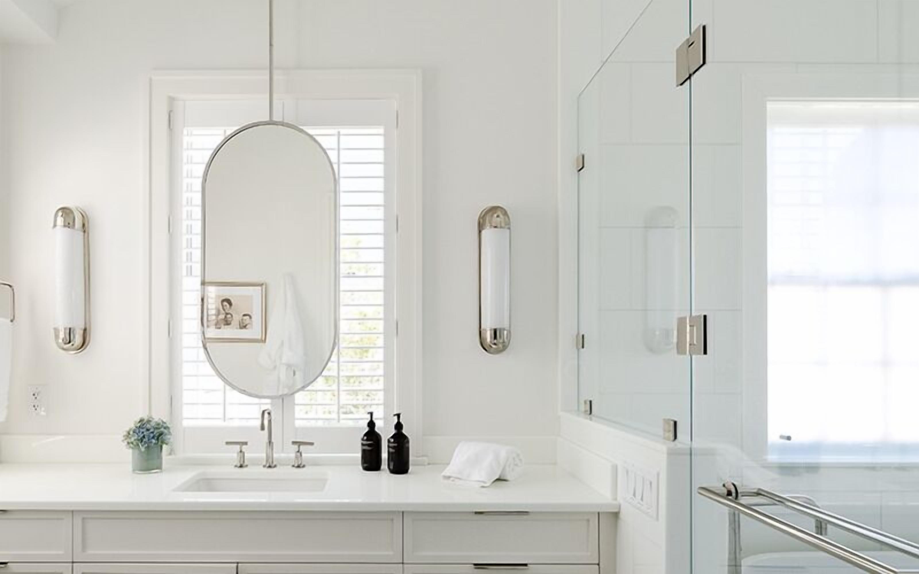 A modern bathroom with a large mirror, a sink, and a glass shower enclosure.
