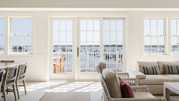 A spacious living area with a view of a marina through large windows. - 2 bedroom, 2.5 bathroom (Nantucket)
