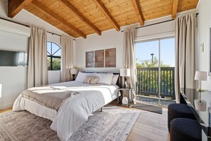 Ein Schlafzimmer mit Bett, Nachttischen, einem Fenster und einem Balkon.