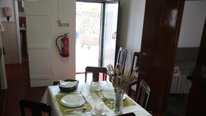 Een eetgedeelte met een tafel voor vier personen, een brandblusser en een deur naar buiten.