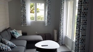 Ein modernes Wohnzimmer mit einer Couch, einem runden Couchtisch und einem Fenster mit Vorhängen.
